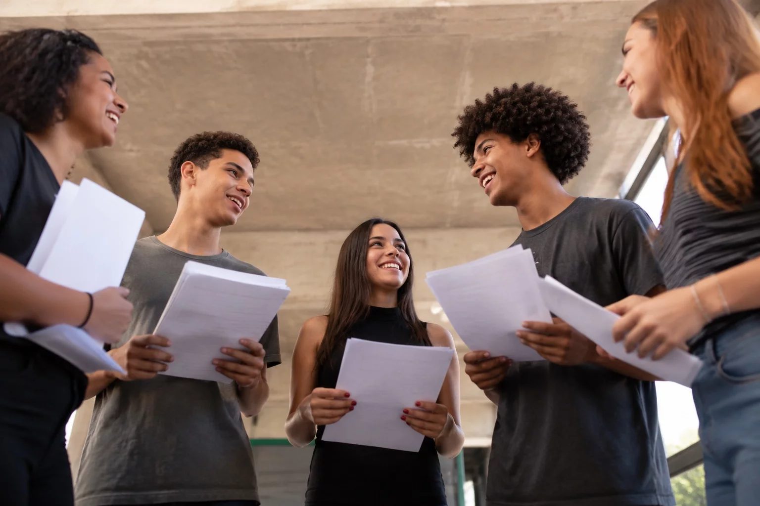 Grupo sorrindo após uma rodada de debate, com papéis nas mãos